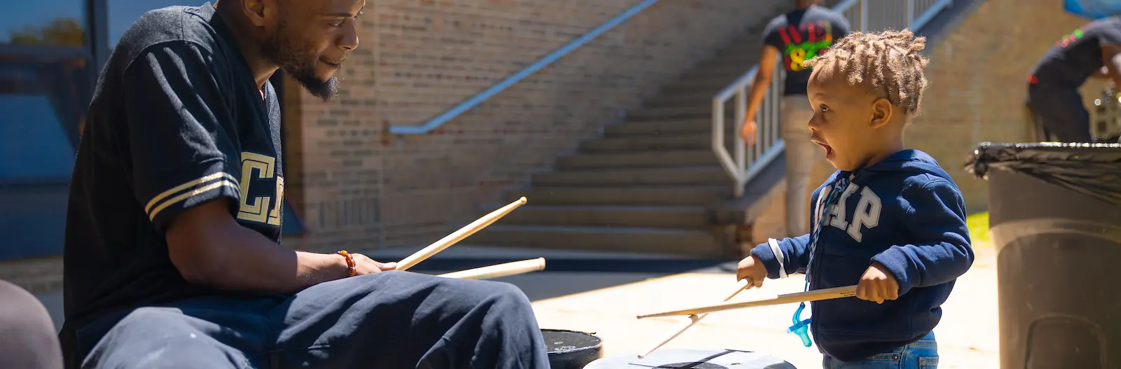 adult playing drums with a little boy