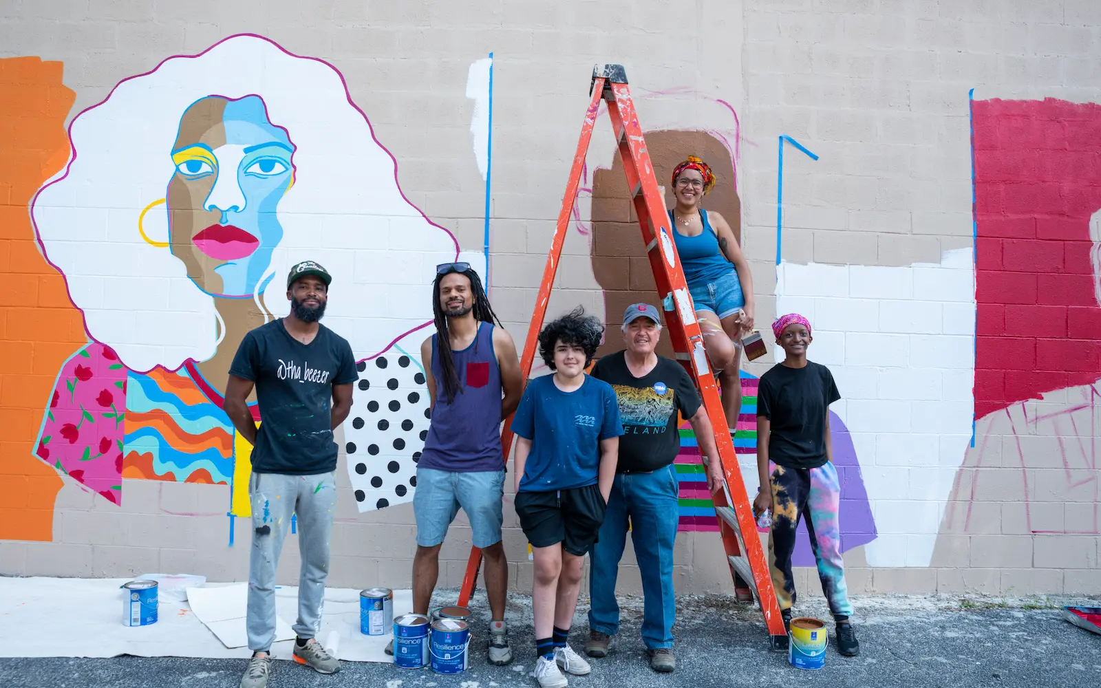 a group of artists stand in front of a mural